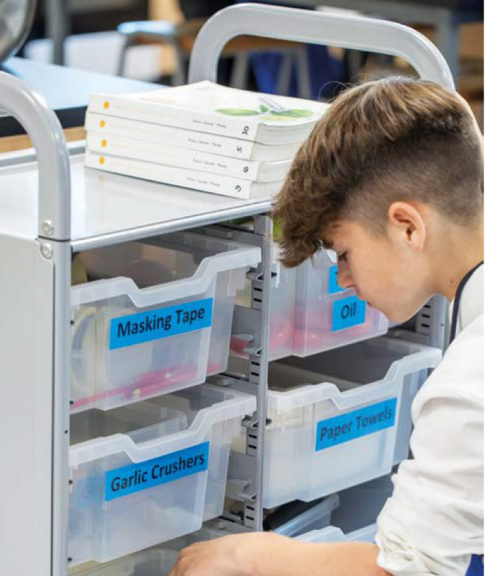 Pupil looking through Gratnells deep trays within a Callero double column trolley.
